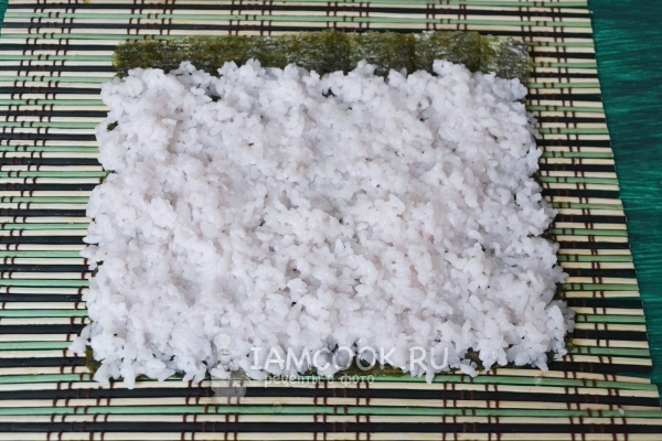 Положить на лист нори рис