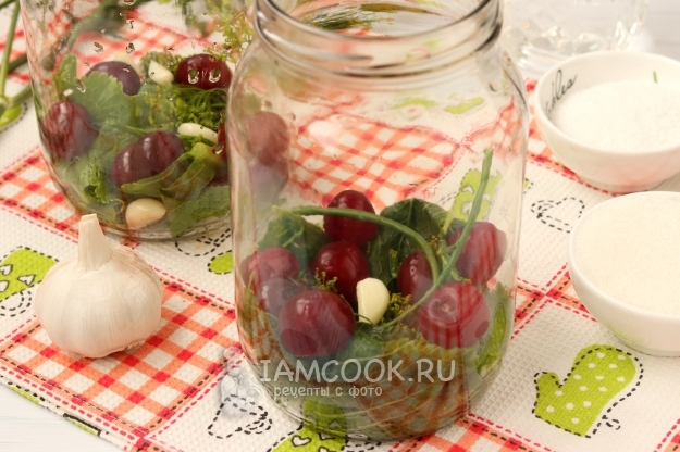Положить в банку зелень, чеснок и вишню