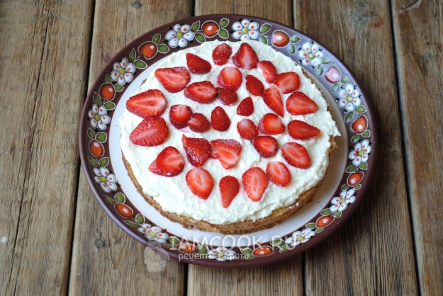 Положить на корж крем и клубнику