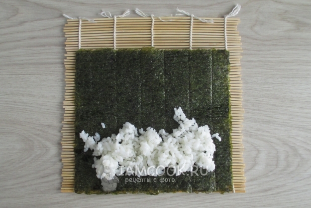 Положить на лист нори рис