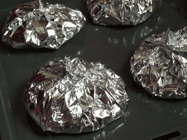 Положить мешочки из фольги на противень