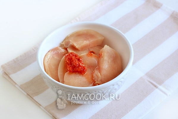 Положить аджику к куриному филе