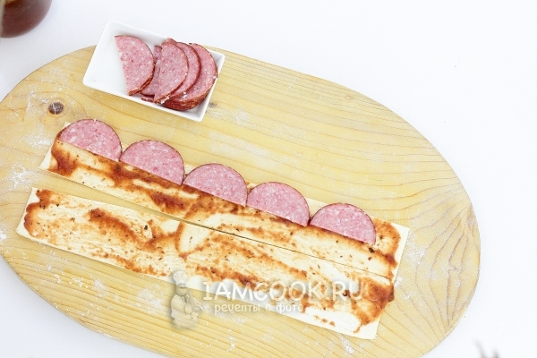 Выложить на тесто колбасу