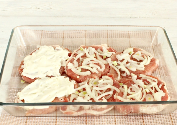 Положить на мясо лук и майонез