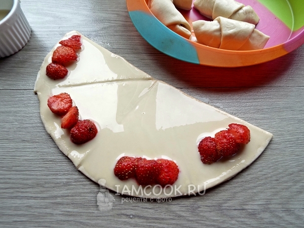 Положить на тесто клубнику