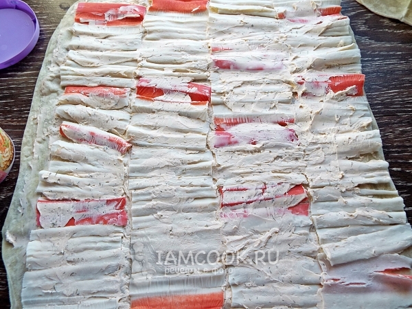 Смазать крабовые палочки сыром