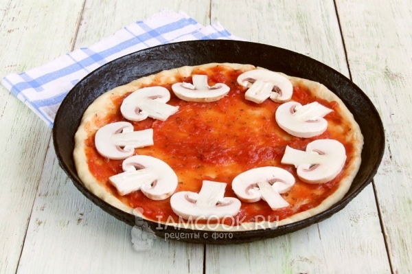 Положить на тесто соус и грибы