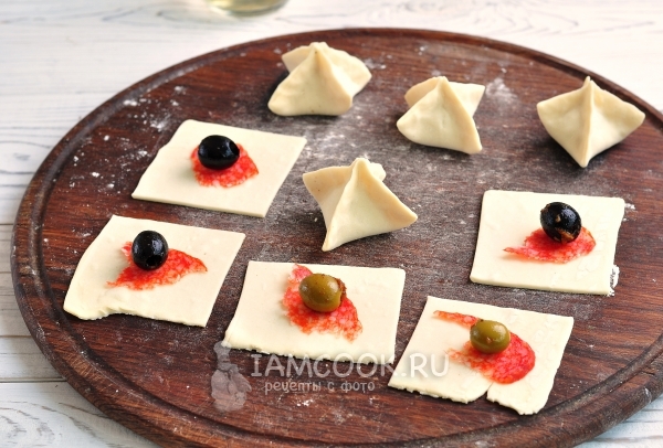 Положить на тесто колбасу и оливку