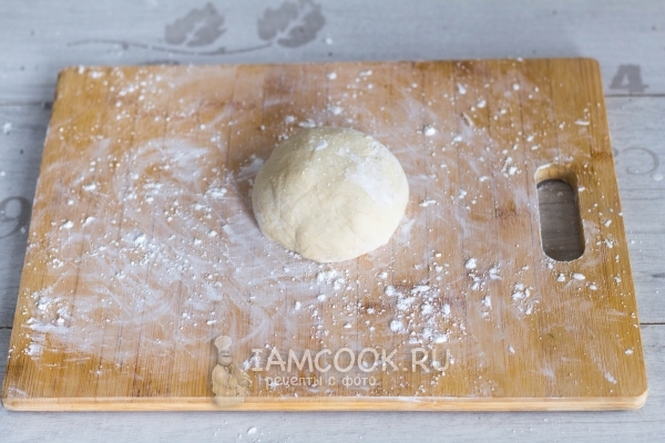 Положить тесто на доску с мукой