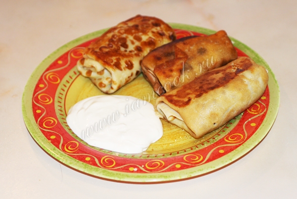 Блины с мясом на тарелке со сметаной