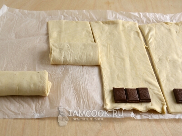 Положить на тесто шоколад и свернуть в рулет