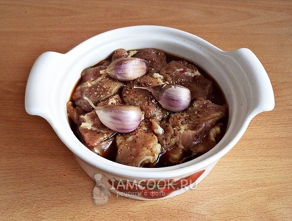 Залить мясо маринадом и положить чеснок