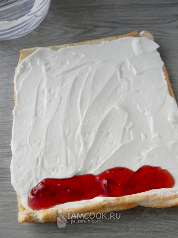 Выложить на бисквит крем и джем