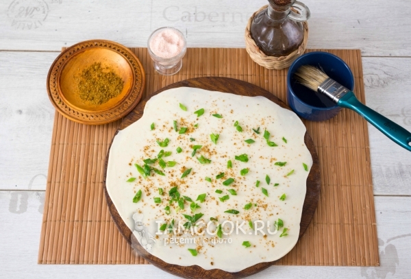 Посыпать тесто специями и луком