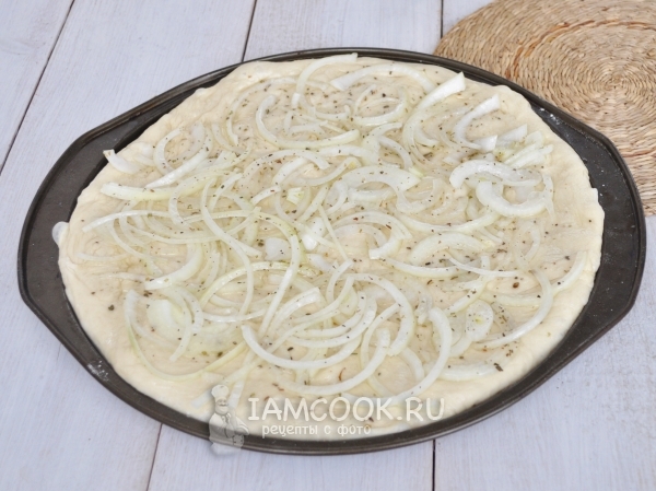 Тесто смазать маслом и положить на него лук