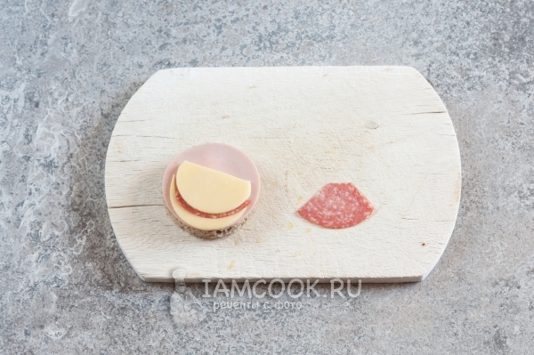 Положить на колбасу сыр и салями