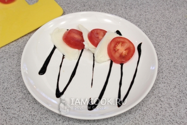 Полить тарелку бальзамическим уксусом и положить сыр с помидором