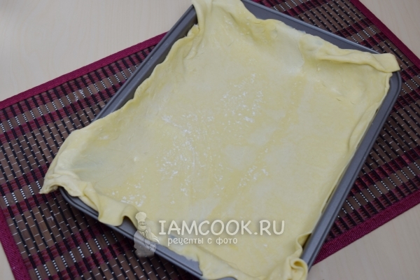 Положить на противень слоеное тесто