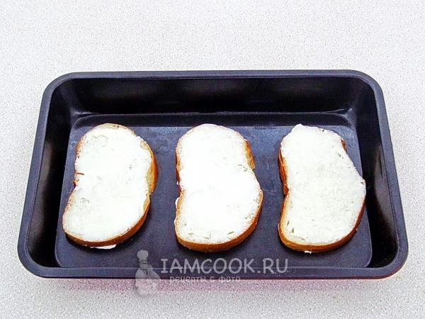 Положить батон с маслом на противень